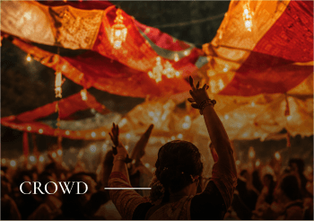 Crowd: festival-goers under warm lights and colourful canopies